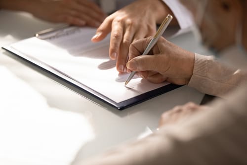 Person signing documents on a clipboard